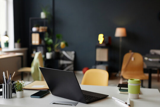 Black laptop computer on workplace desk in modern minimal office setting copy space