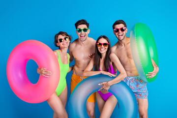 Photo of good mood cool buddies company dressed bikini going swim inflatable rings isolated blue...