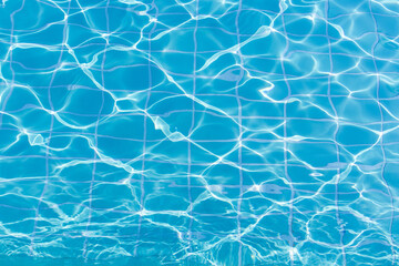 Blue swimming pool water surface and ripple wave background. Summer abstract reflection caustics in swimming pool.