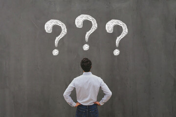 business man looking at questions on chalkboard, ask questions, FAQ concept, uncertainty,...