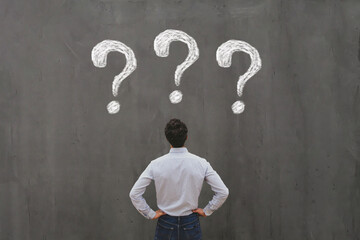 business man looking at questions on chalkboard, ask questions, FAQ concept, uncertainty,...