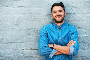 Portrait, man and smile against brick wall for confidence, pride or fashion with mockup in city. Male person, crossed arms and denim outdoors in urban town for creative career, tourist or student