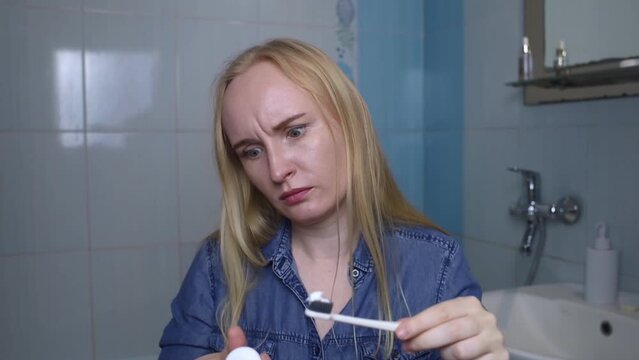Toothpaste ingredients. Girl checks composition of toothpaste and is surprised by dangerous composition of product. Emulsifiers, preservatives, dyes, PEG, SLS, parabens, diethanolamine