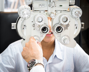 India cute boy sitting in an eyeglass shop with an optometrist specializing in eye disorders and primary eye health looking for a lens to suit his eyesight and get the most effective eyeglasses.