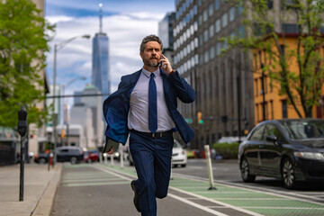 Man in suit with phone run in NY. Business talk. Businessman run down street talking on the phone. Man in suit late. Business call. Running business man. Fast business. Run and late businessman.