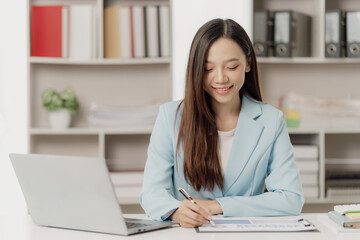 Asian businesswoman working using a laptop computer Marketing report with calculator document on table Plan to analyze financial reports