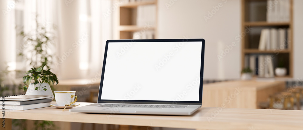 Canvas Prints a laptop computer mockup on a wooden tabletop in a contemporary minimalist cafe co-working space.