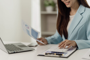 Asian businesswoman working using a laptop computer Marketing report with calculator document on...