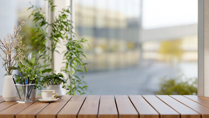 A wooden tabletop features a coffee cup and potted plants against the window in a room.