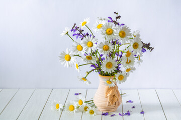Beautiful bouquet of daisies flowers in a vase on a white wooden table