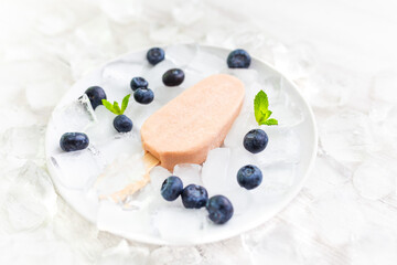 Berry ice cream with blueberries on a stick with ice. White background.  