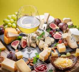 Glass of white wine with variety of sliced cheeses.