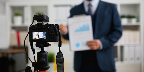 Male in suit and tie show stats graph pad making promo videoblog or photo session in office...