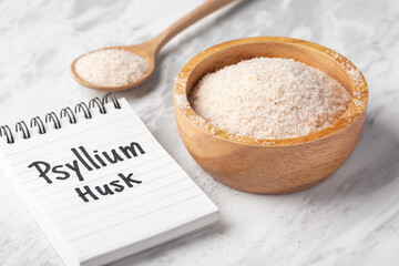 Psyllium husk in wooden bowl with psyllium husk word on notebook on marble table