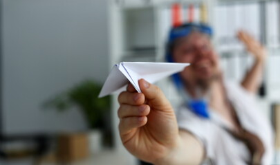 Man wearing suit and tie in goggles and snorkel play with fly paper plane in office closeup. Count...