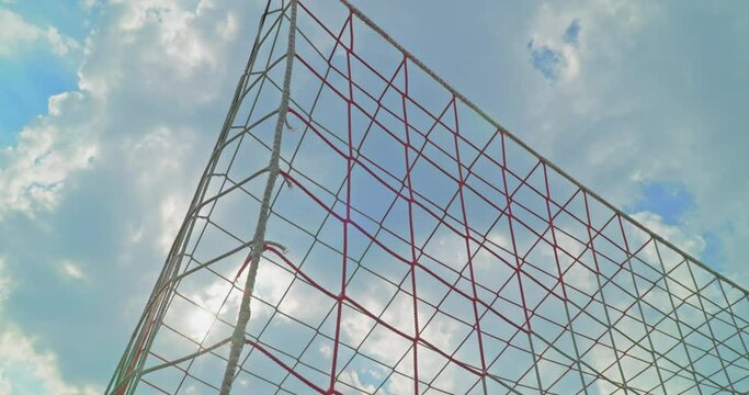 Soccer field impressions - A soccer ball hitting the net and scoring a goal - Handheld slow-mo, filmed from behind the goal and against the sun