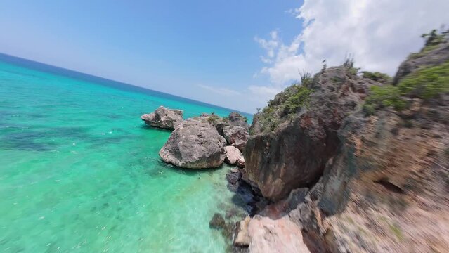 Fpv drone flight over rocky coastline of Bahia de aguilas in Dominican Republic. Sunny day with clear water of Caribbean Sea.