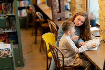 in bookstore near the window a young mother sits teaching her son to read child development