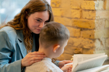 close up in bookstore near the window a young mother sits teaching her son to read child development