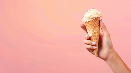 Delicious ice cream cone in hand, tempting summer treat on vibrant peach background. 
