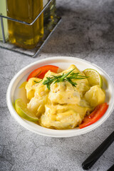 Potato salad with tomatoes and lemon on gray stone table