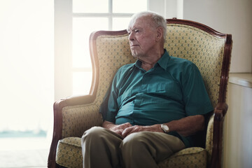 Fototapeta premium Nursing home, senior and man on couch, depression and memory in living room, patient and healthcare of person. House, lounge and wellness for Alzheimers, retirement and thinking for treatment