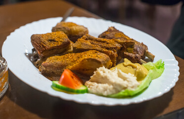 grilled meat and vegetables on a white plate in a restaurant.