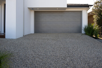 Exposed Aggregate concrete surface driveway with a locked garage door of a new modern suburban...