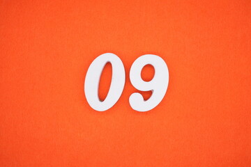 The number 09 is made from white painted wood placed on a background of orange paper.