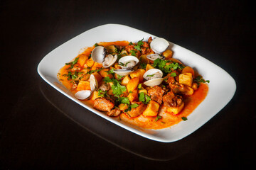 Traditional Portuguese dish: Pork Alentejana. Tender pork marinated in spices, served with clams and potatoes. Authentic taste of Portugal.