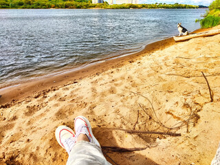 Human feet on a sandy beach. The concept of tourism and recreation. Relaxing Feet on a Sandy Shoreline at Sunset
