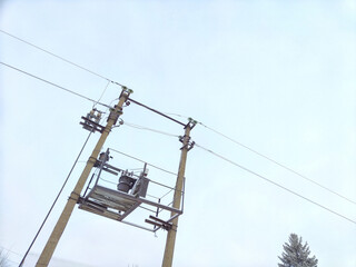 Old power line pole and transformer against blue sky in sunny day