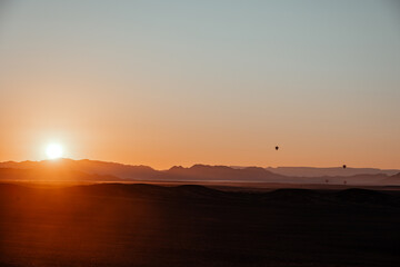 hot air balloons in sossusvlei national park at sunrise with the orange dunes as backdrop, namibia