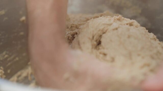 Sourdough bread dough kneading in a bowl, closeup on hands