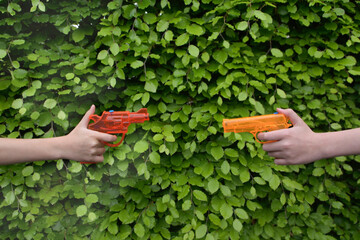 Two children dueling with a toy water gun, Close-up against summer foliage