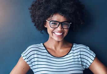 Portrait, afro and black woman with glasses, fashion and happiness on blue studio background....