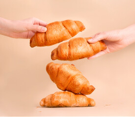 Croissants in hands on a beige background