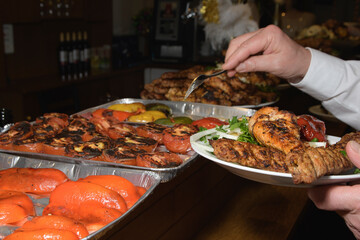 A man chooses tomatoes and paprika fried for meat in a restaurant buffet