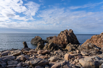 Scenic view of a rocky shoreline featuring jagged rocks and a small tower in Varberg, Sweden