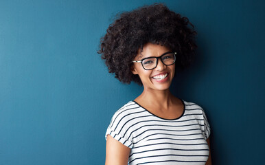 Black woman, portrait and smile with glasses for optometry or vision and on blue studio background....