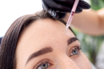 Beauty injections. Female cosmetologist in black gloves makes an injection