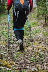 Person in shorts with hiking poles, backpack exploring woods