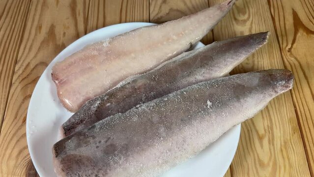 Raw frozen fillets of hake in ice glaze on plate