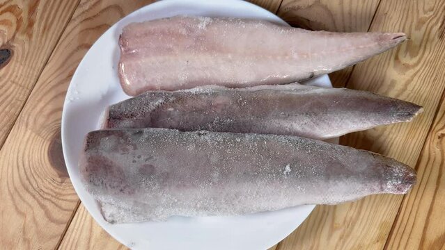 Raw frozen fillets of hake in ice glaze on plate