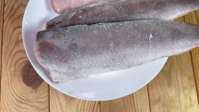 Raw frozen fillets of hake in ice glaze on plate