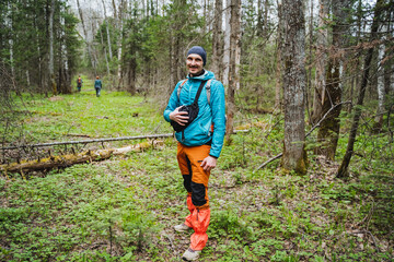 Man wearing blue jacket and orange pants standing in forest