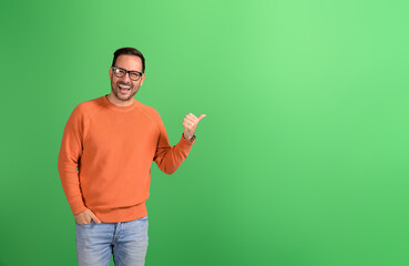 Portrait of happy businessman pointing aside and advertising commercial service on green background
