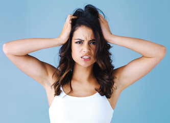 Fototapeta premium Woman, frustrated and hair care in studio portrait with mess, angry or cosmetics by blue background. Girl, shock and confused for hairstyle with bad results, stress or crisis for change with disaster