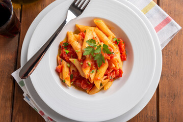 Piatto di deliziose penne all'arrabbiata, tradizionale ricetta di pasta della cucina romana, cibo italiano 