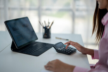 A woman is sitting at a desk with a laptop and a calculator